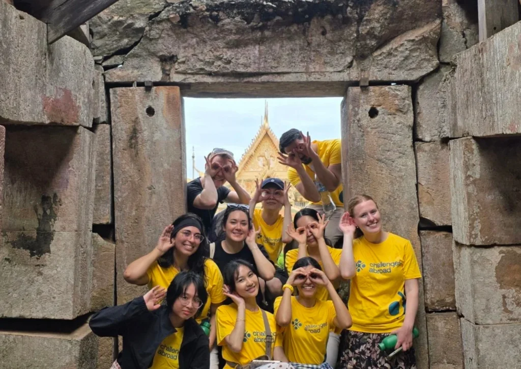 A cheerful group poses creatively at an ancient stone doorway, showcasing their adventurous spirit during a cultural...