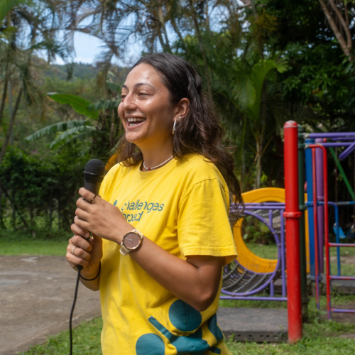 Smiling volunteer holding a microphone while leading an outdoor activity in a playground